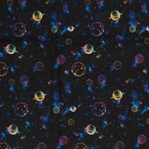 May include: A black fabric with a repeating pattern of planets and stars in rainbow colors. The planets have rings and are surrounded by a galaxy of stars.