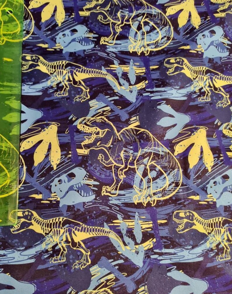 May include: A blue and yellow dinosaur skeleton pattern fabric with a repeating design of dinosaurs and footprints.