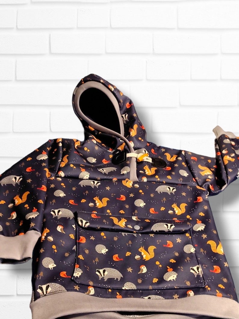 May include: A dark blue hooded sweatshirt with a pocket and a pattern of squirrels, hedgehogs, and birds on a white background.