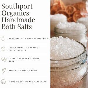 May include: Close-up of glass jars filled with white bath salts. The jars are in focus, with a blurred background of more jars and dried orange slices. Text on the left reads "Southport Organics Handmade Bath Salts". Additional text highlights the product's benefits.