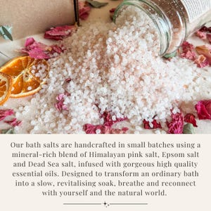 K&ouml;nnte beinhalten: Ein Glasgef&auml;&szlig;, aus dem grobes rosa und wei&szlig;es Badesalz auf eine mit getrockneten rosa Rosenbl&auml;ttern und einer dehydrierten Orangenscheibe bestreute Fl&auml;che rieselt. Die Salzmischung besteht aus Himalaya-Salz, Epsom-Salz und Totem-Meer-Salz.