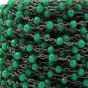 Puede incluir: Primer plano de una cadena de piedras preciosas verdes con eslabones de metal negro. La cadena está hecha de cuentas facetadas y es perfecta para la elaboración de joyas.