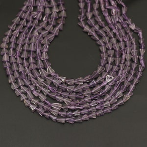 Peut inclure: Plusieurs brins de perles de pierres précieuses d'améthyste. Les perles sont de couleur violet clair et ont la forme de petits cônes inversés. Les perles sont enfilées ensemble, créant une apparence de collier. Le fond est gris foncé.