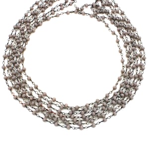 Könnte beinhalten: Eine mehrreihige Halskette aus grauen Perlen und einer silbernen Kette.