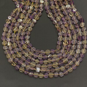 Peut inclure: Gros plan sur des brins de perles de pierres précieuses. Les perles sont un mélange de violet et de jaune-brun, de forme plate et en forme de disque. Les perles sont enfilées sur un fil jaune fin, créant un effet de superposition. Le fond est gris foncé.