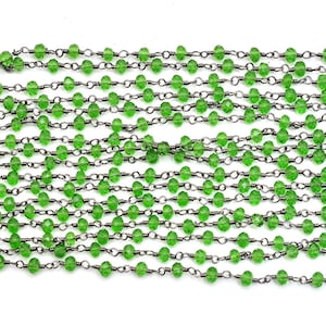 Puede incluir: Cadenas de cuentas verdes facetadas unidas con eslabones de metal oscuro. Las cuentas son de un verde vibrante y translúcido, y la cadena tiene un acabado oscuro y oxidado. Las cuentas están espaciadas uniformemente a lo largo de la cadena.
