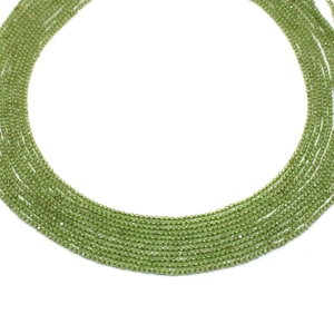 Peut inclure: Plusieurs brins de petites perles rondes vert clair. Les perles sont enfilées ensemble, formant plusieurs brins. Les perles sont de taille et de couleur uniformes, créant une apparence uniforme. Le fond est blanc uni.