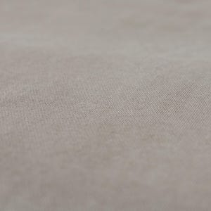 Puede incluir: Primer plano de una tela beige claro con una textura sutil. La tela tiene una superficie lisa y uniforme con un ligero brillo.