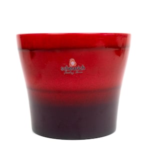 May include: Red and black ombre ceramic planter with the text "scheurich Pottery Design" in white.