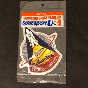 May include: An iron-on patch featuring the Space Shuttle Columbia, with the text "Columbia", "YOUNG - CRIPPEN", and "Spaceport USA" on it.