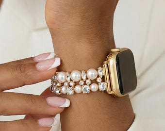 May include: Gold-tone Apple Watch with a pearl and crystal band. The band features multiple rows of white pearls and clear crystals. The watch is on a wrist, and the text "POLY BANDS" is visible at the bottom of the image.