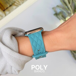 Puede incluir: Una banda de reloj Apple de silicona azul turquesa con un patr&oacute;n acolchado y detalles en oro rosa. La banda se muestra en la mu&ntilde;eca de una persona. El texto "POLY BANDS" es visible en la parte inferior de la imagen.