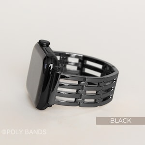 May include: Black watch band with a woven design. The watch face is black and rectangular. The band is made of metal and has a series of horizontal and vertical bars. The word "BLACK" is printed on a light brown rectangle.
