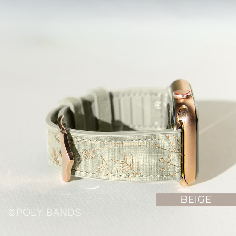 Op de afbeelding: Een beige Apple Watch band met een bloemenpatroon en ros&eacute;gouden hardware. De band is gemaakt van een zacht, getextureerd materiaal en heeft een klassieke uitstraling.