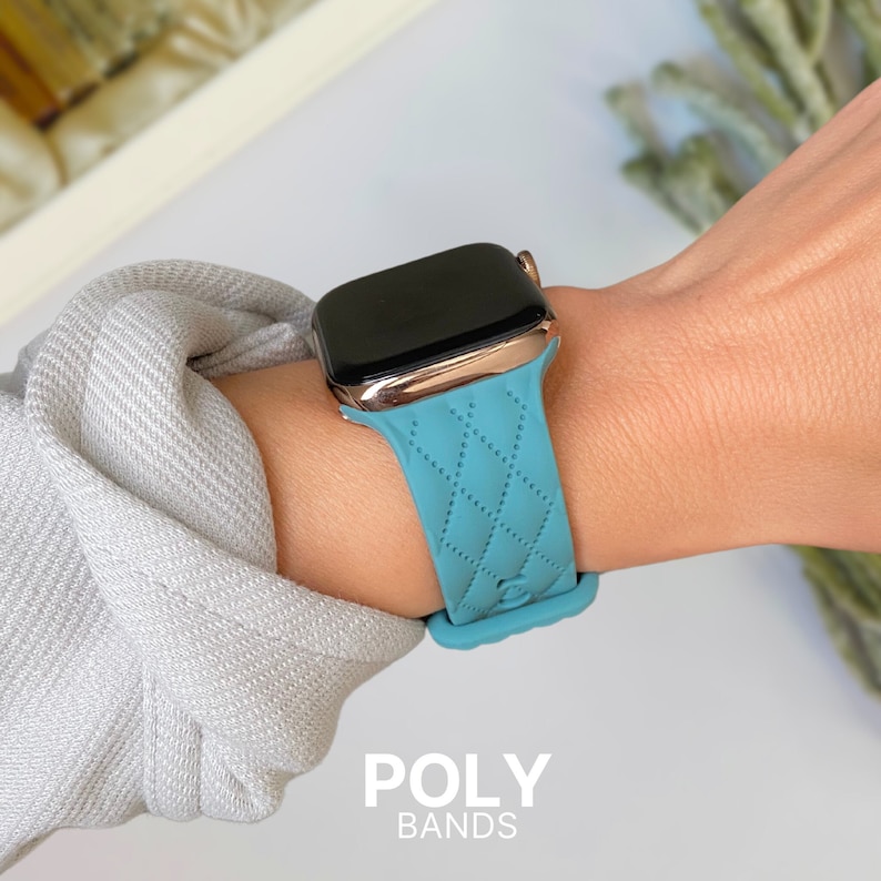 Puede incluir: Una correa de reloj de silicona azul claro acolchada con un Apple Watch de oro rosa.