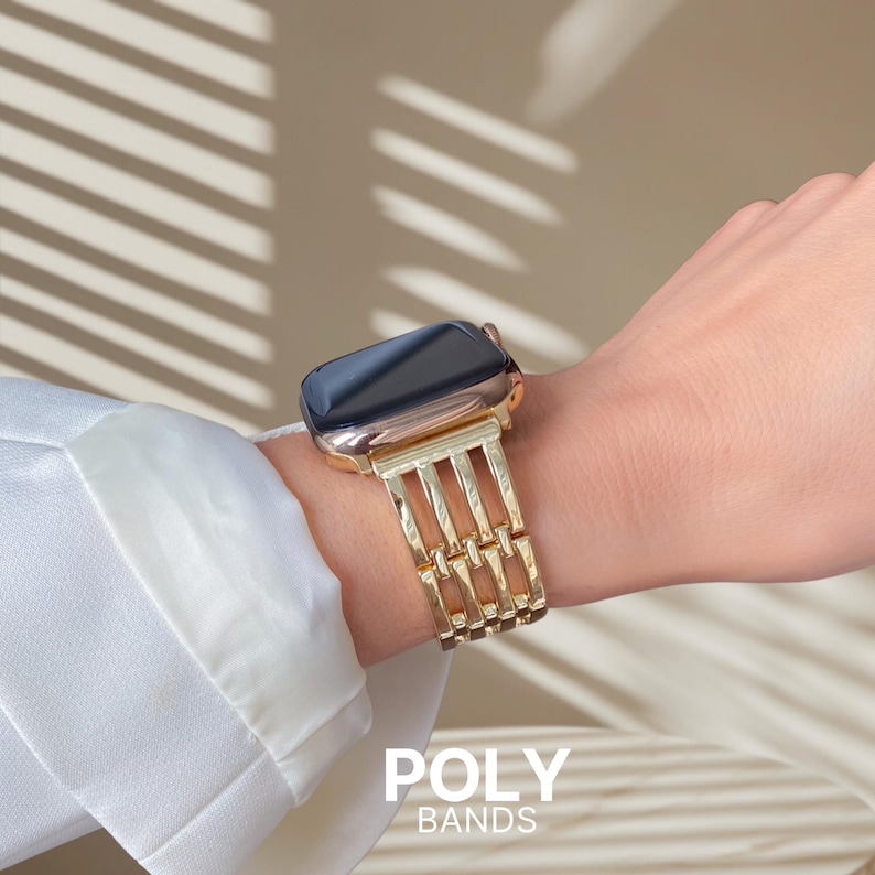 May include: A gold-colored watch band with a geometric design is displayed on a wrist. The watch face is black. The text "POLY BANDS" is visible at the bottom of the image.
