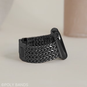 May include: A black braided metal Apple Watch band with a black metal clasp. The band is made of a woven metal design.