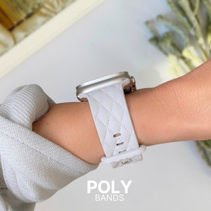 Puede incluir: Banda de reloj blanca acolchada con una hebilla plateada. La banda est&aacute; en la mu&ntilde;eca de una persona. El texto "POLY BANDS" est&aacute; en la parte inferior de la imagen.