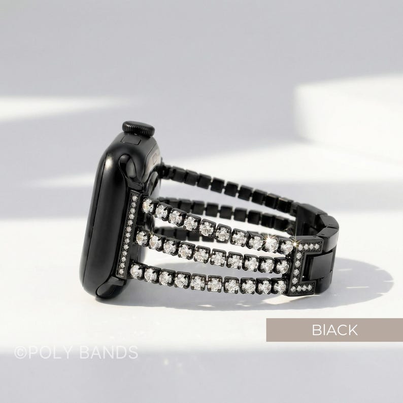 May include: Black Apple Watch with a three-row rhinestone band. The watch band is black with three rows of clear rhinestones. The watch is on a white surface. The text "BIACK" is in the bottom right corner, and "OPOLY BANDS" is in the bottom left corner.