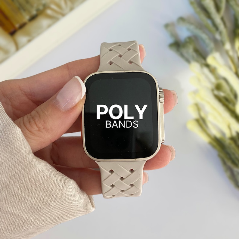 May include: A beige braided watch band with a gold Apple Watch face that says "POLY BANDS" on the screen.