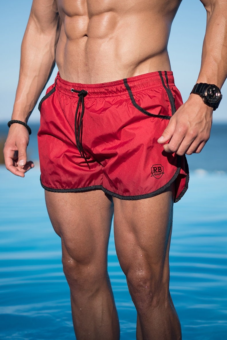 K&ouml;nnte beinhalten: Rote Badeshorts mit schwarzem Besatz und Kordelzug. Die Shorts haben ein kleines Logo am Bein. Die Shorts sind f&uuml;r Schwimmen und Wasseraktivit&auml;ten konzipiert.