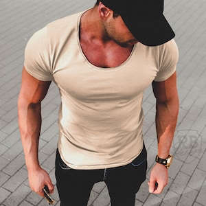 Könnte beinhalten: Ein beiges T-Shirt mit Rundhalsausschnitt und kurzen Ärmeln. Das T-Shirt ist aus einem weichen, bequemen Material gefertigt.