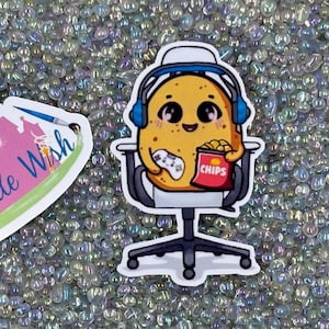 May include: Two colorful stickers on a white background. The first sticker is pink and white and features a castle with the text "The Castle Wish". The second sticker is white and features a cartoon potato wearing headphones and holding a video game controller and a bag of chips.