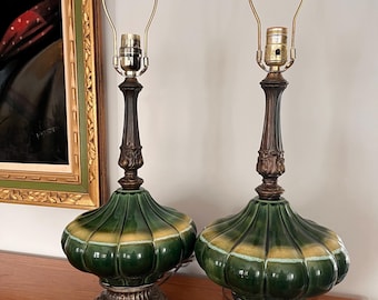 May include: A pair of green and gold ceramic table lamps with ornate brass bases. The lamps have a scalloped design and a vintage style.