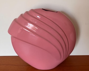 May include: A pink ceramic vase with a unique, wavy design. The vase is round and has a wide opening.