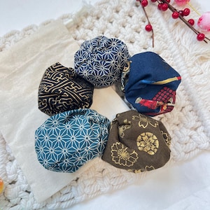 May include: A set of five fabric hair scrunchies featuring various patterns including a dark blue geometric star print, a black and gold maze design, a blue and white star pattern, a brown floral print, and a dark blue samurai warrior graphic.