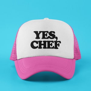 May include: A pink and white trucker hat with the text "YES, CHEF" in black.