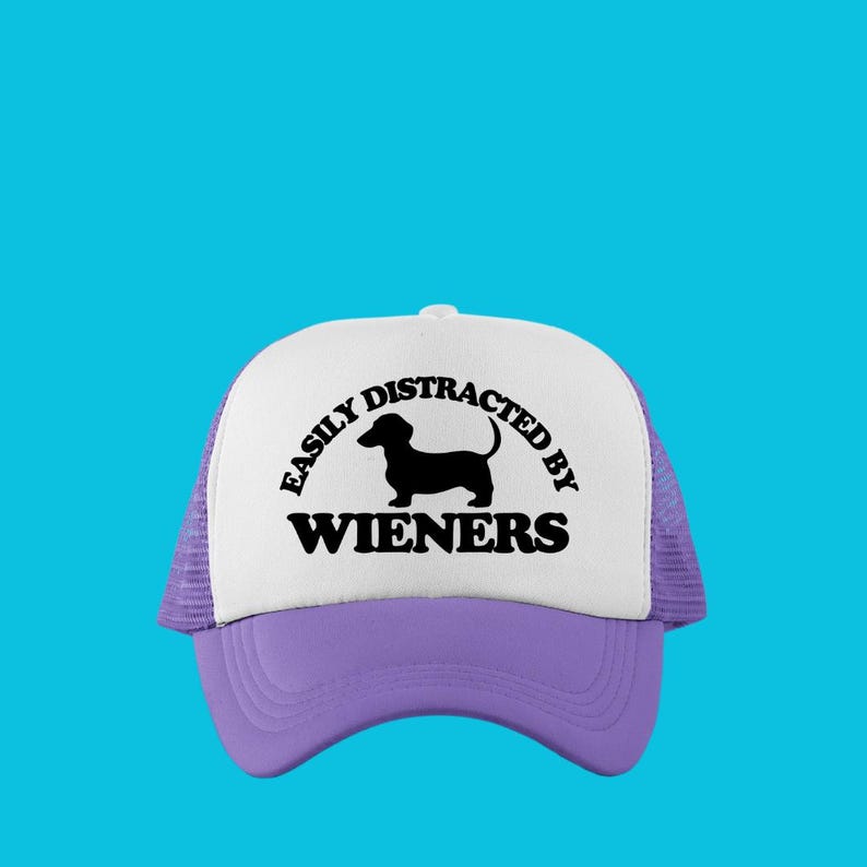 K&ouml;nnte beinhalten: Eine wei&szlig;e und lilafarbene Trucker-Kappe mit einer schwarzen Dackel-Silhouette und dem Text "Easily Distracted By Wieners".
