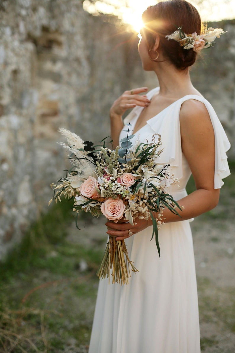 Medium size free form salmon rose bridal bouquet with preserved roses, pampas grass, eucalyptus and gypsophila, held by bride at sunset — elegant boho rustic dried wedding flowers handmade by GulFloraWedding.