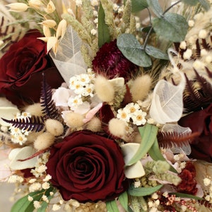 May include: A bouquet of dried flowers with burgundy roses, white baby's breath, and dried grasses.