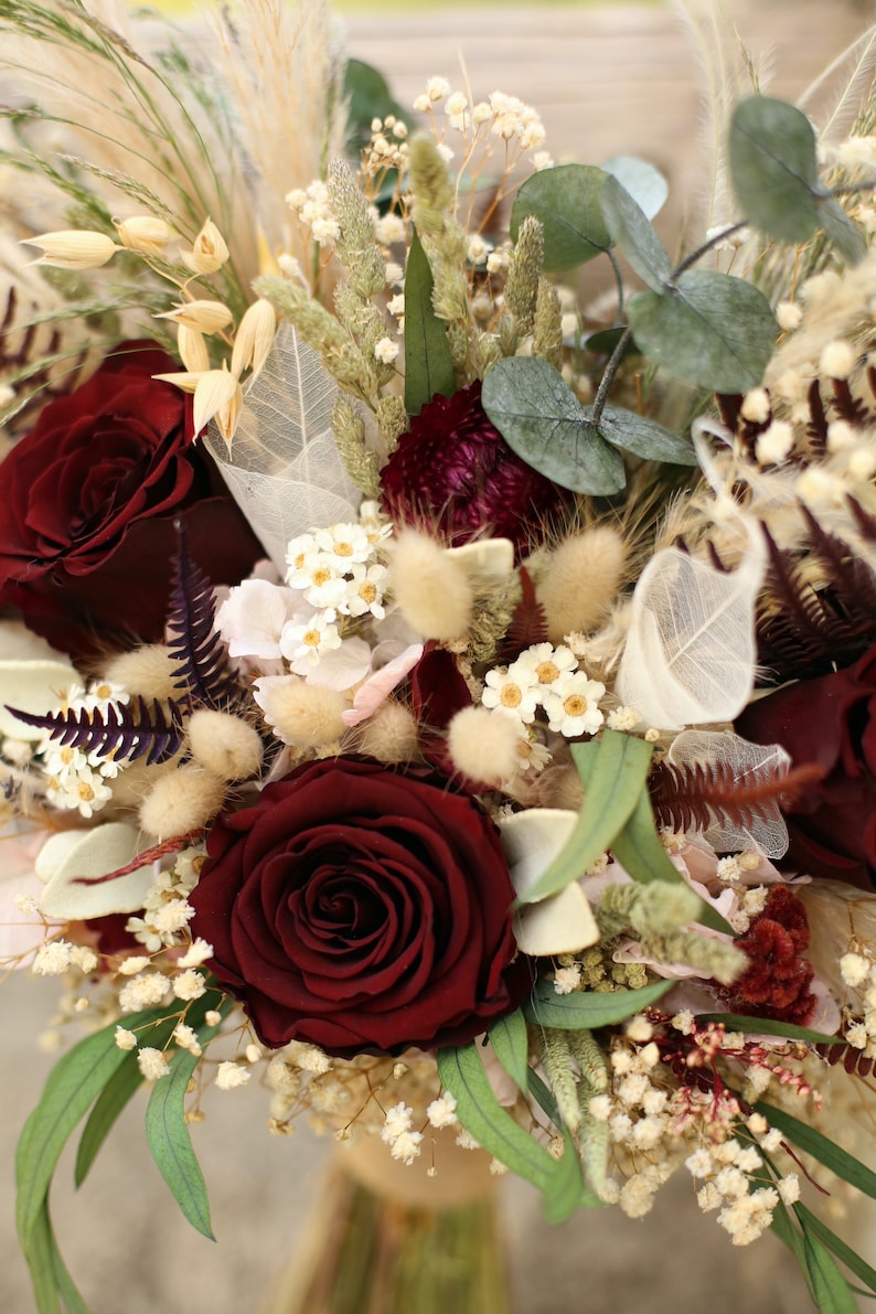 May include: A bouquet of dried flowers with burgundy roses, white baby's breath, and dried grasses.