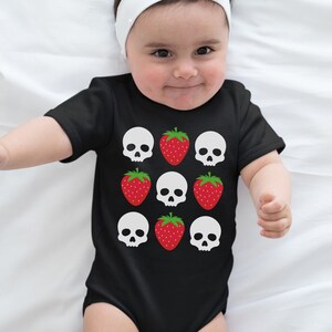 May include: A black baby onesie with a white skull and red strawberry pattern.
