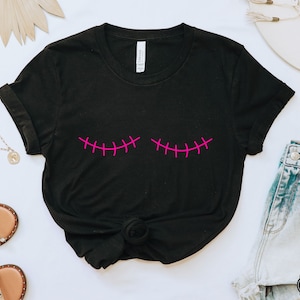 Puede incluir: Camiseta negra con un diseño de sonrisa cosida rosa.