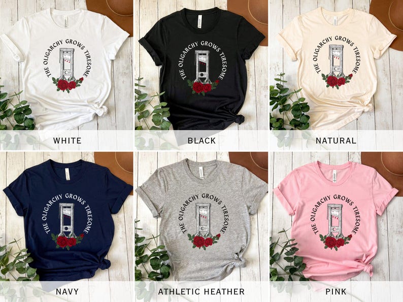 May include: A collection of t-shirts in various colors, including white, black, navy, and pink. Each shirt features a guillotine graphic with the text "THE OLIGARCHY GROWS TIRESOME" in a circular design, surrounded by red roses.