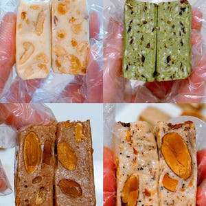 May include: A collage of four rectangular nougat bars featuring various inclusions. The top left shows a creamy white bar with light brown nuts. The top right is a textured green bar with dark flecks. The bottom left is a brown bar with whole almonds. The bottom right is a beige bar with large almond pieces.