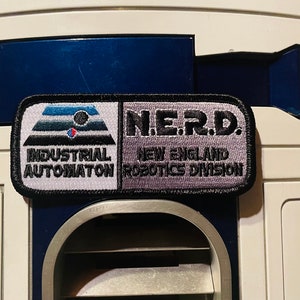 May include: A black and white patch with the text "INDUSTRIAL AUTOMATION" and a gray patch with the text "N.E.R.D. NEW ENGLAND ROBOTICS DIVISION".