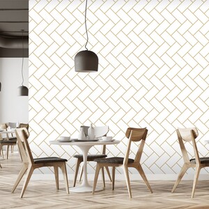 May include: A dining room with a white wall featuring a gold geometric pattern wallpaper. The room is furnished with a wooden table, four chairs, and a hanging light fixture.