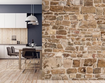 May include: A modern kitchen with a dining table and chairs. The table is made of wood and has a light brown finish. The chairs are black and have a metal frame. The kitchen has a white countertop and cabinets. The wall behind the table is made of stone.