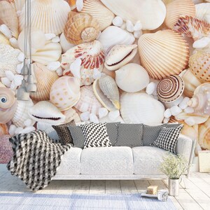 Könnte beinhalten: Ein weißes Sofa mit schwarz-weißen Kissen steht vor einer Wand, die mit verschiedenen Muscheln bedeckt ist. Die Muscheln sind in Weiß-, Braun- und Beigetönen gehalten.