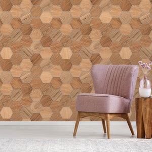 May include: A pink armchair with wooden legs sits in front of a wall covered in a hexagonal wood-patterned wallpaper. A small wooden side table with a vase of flowers sits next to the chair.