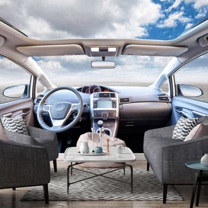 May include: A car interior with a sunroof, two gray couches, a coffee table, and a blue sky visible through the sunroof.