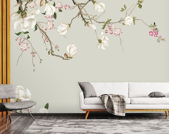 May include: A white couch with a gray throw blanket sits in front of a wall with a floral mural. The mural features a white magnolia branch with pink flowers and green leaves.