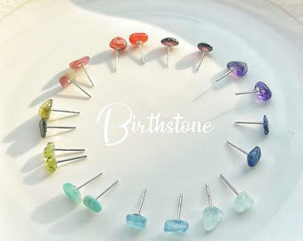 May include: A set of 12 birthstone earrings, each featuring a different gemstone. The earrings are arranged in a circle on a white plate. The gemstones are: Garnet, Amethyst, Aquamarine, Diamond, Emerald, Alexandrite, Ruby, Peridot, Sapphire, Opal, Topaz, and Turquoise.