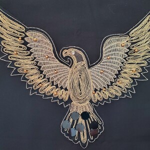 May include: A gold embroidered eagle with black sequins on a black background.