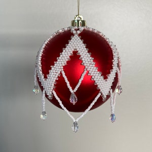 May include: A red Christmas ornament with a white beaded design and crystal drops.