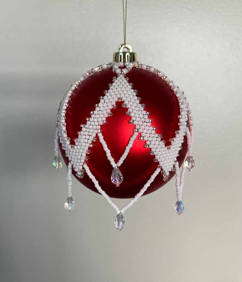 May include: A red Christmas ornament with a white beaded design and crystal drops.